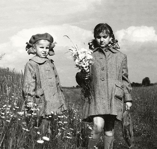 Schwarzweißaufnahme Zwei Mädchen auf einem Blumenfeld in der DDR